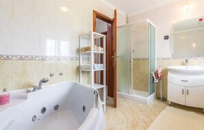 Bathroom features a large bathtub, glass-enclosed shower, and sink with mirror.