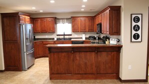 A kitchen with wooden cabinets, a stainless steel refrigerator, and a central island. - Quiet and Comfortable!  5 minutes away from parks/hospitals (Joplin)