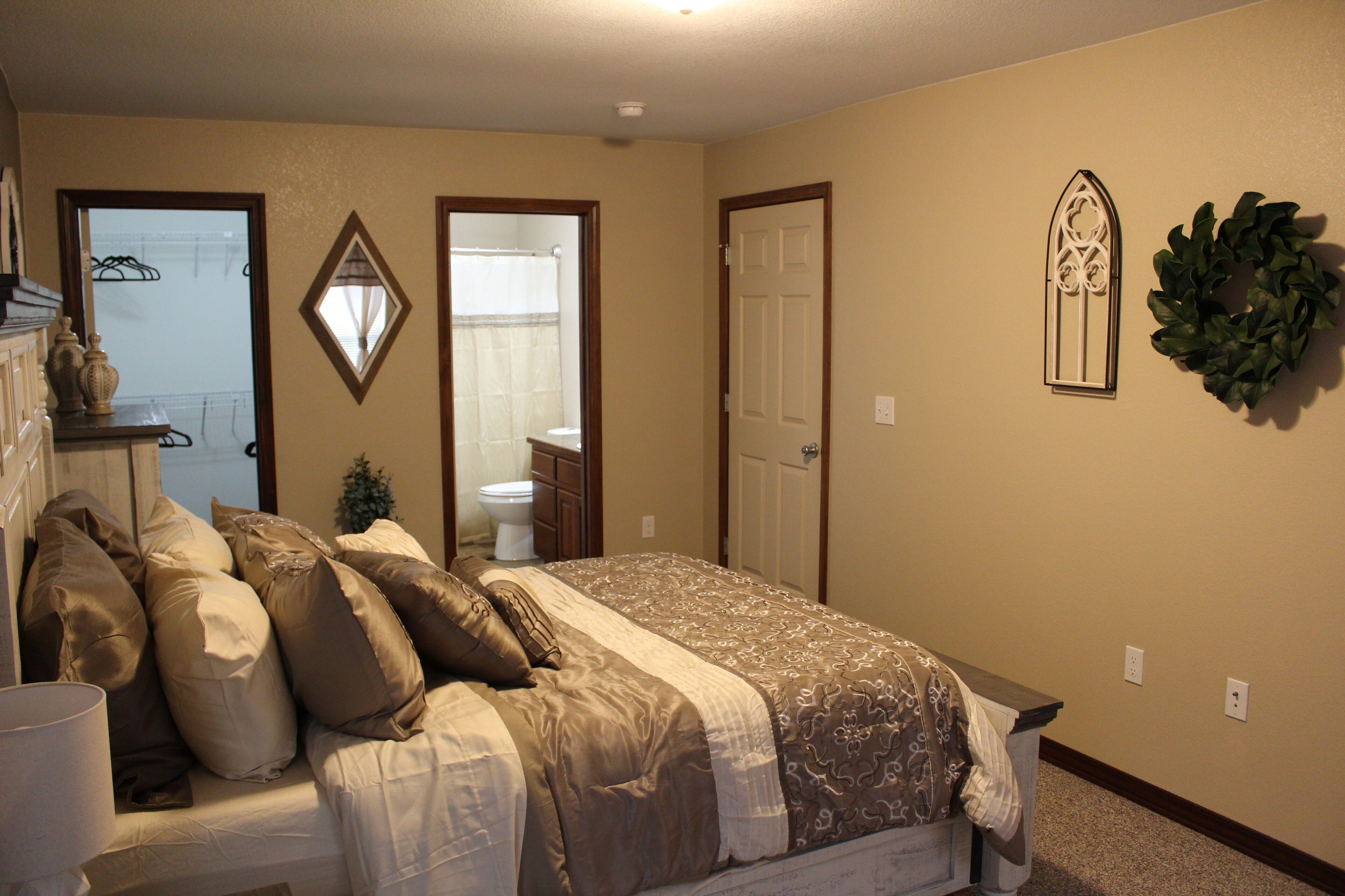 A bedroom with a bed, a dresser, a mirror, and a door.