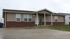 A two-story building with a brick facade and a covered front porch. - Quiet and Comfortable!  5 minutes away from parks/hospitals (Joplin)