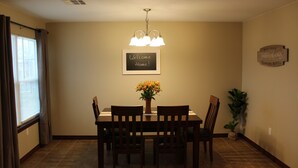 A dining area with a table, chairs, a chandelier, a welcome sign, and a plant. - Quiet and Comfortable!  5 minutes away from parks/hospitals (Joplin)