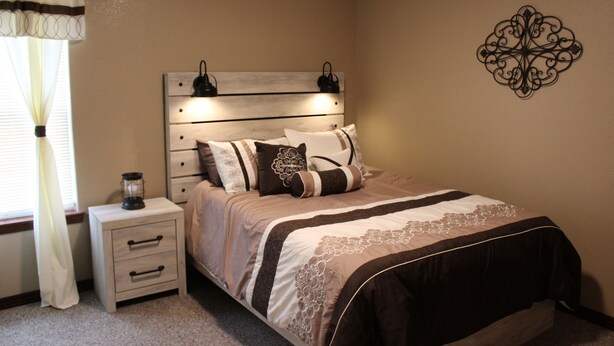 A bedroom with a bed, bedside table, and wall decor. - Quiet and Comfortable!  5 minutes away from parks/hospitals (Joplin)
