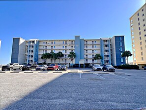 A multi-story hotel with a parking lot in front. - 🌴You CAN afford Paradise! Life is better at the beach. 🌊Call today! (Gulf Shores)