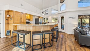 A spacious kitchen with wooden cabinets, a bar area with stools, and a large clock on the wall. - 🌅 Sunset Ranch 🌅 Views Views Views with Private Indoor Pickelball Court (Flagstaff)