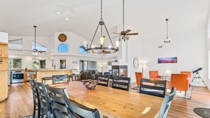 A spacious kitchen with modern appliances, a dining area with a large wooden table and chairs, and a ceiling fan. - 🌅 Sunset Ranch 🌅 Views Views Views with Private Indoor Pickelball Court (Flagstaff)