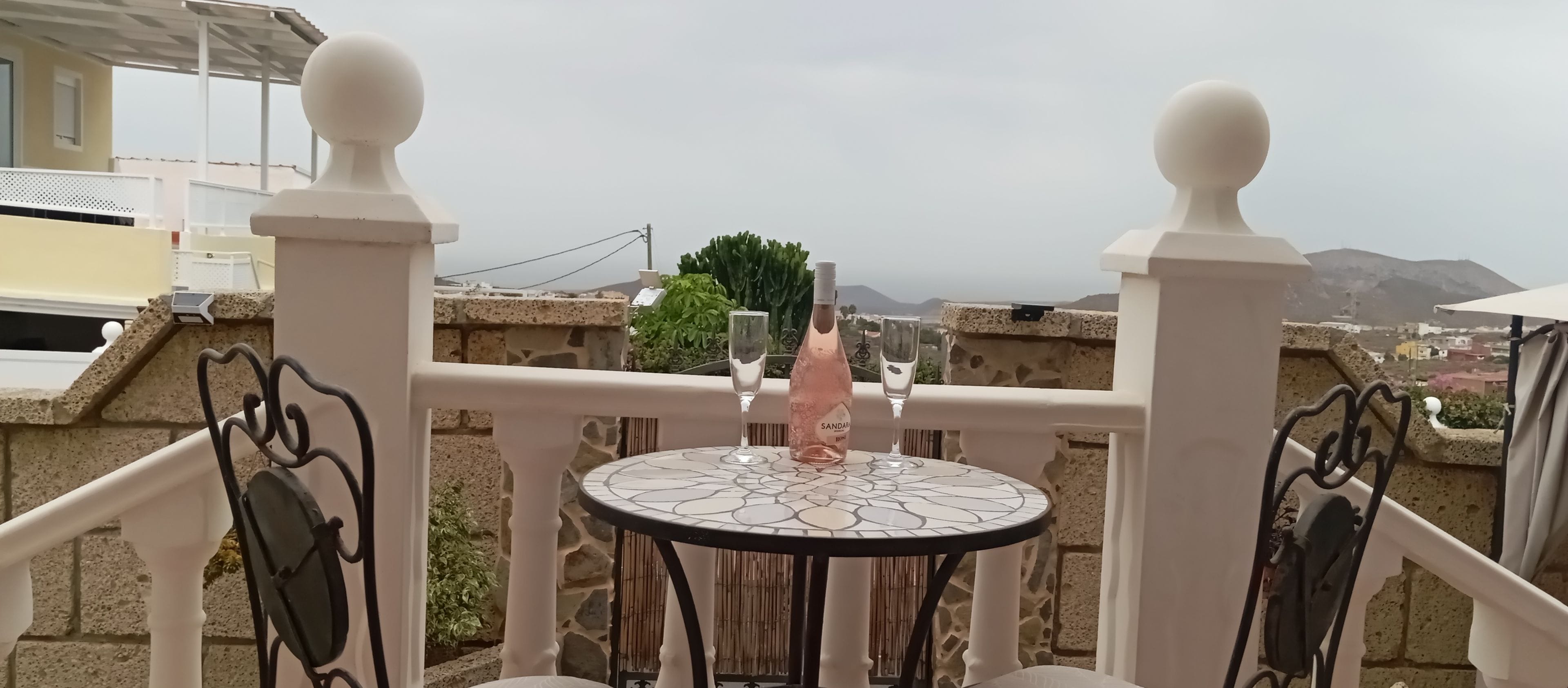 Un balcon avec une table, deux chaises et une bouteille de vin.