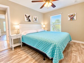 A bedroom with a bed, nightstands, a ceiling fan, and artwork on the walls. - Mystical - Relaxing Heated Pool and Stylish Comfortable Home, Pet Friendly! (St. Augustine)