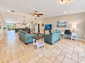 A spacious living area with a sofa set, a dining table, and a TV. - Mystical - Relaxing Heated Pool and Stylish Comfortable Home, Pet Friendly! (St. Augustine)