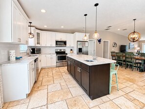 A modern kitchen with white cabinets, stainless steel appliances, and a central island. - Mystical - Relaxing Heated Pool and Stylish Comfortable Home, Pet Friendly! (St. Augustine)