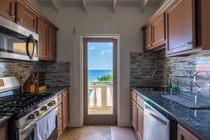 Une cuisine donnant sur la mer, avec une porte-fenêtre.