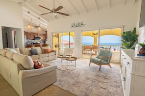 A spacious living area with a sofa, coffee table, and a view of the ocean through large sliding doors.