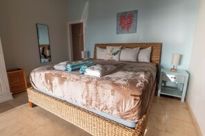 Une chambre à coucher avec un grand lit, un miroir, une porte, une table de chevet et une œuvre d’art murale.