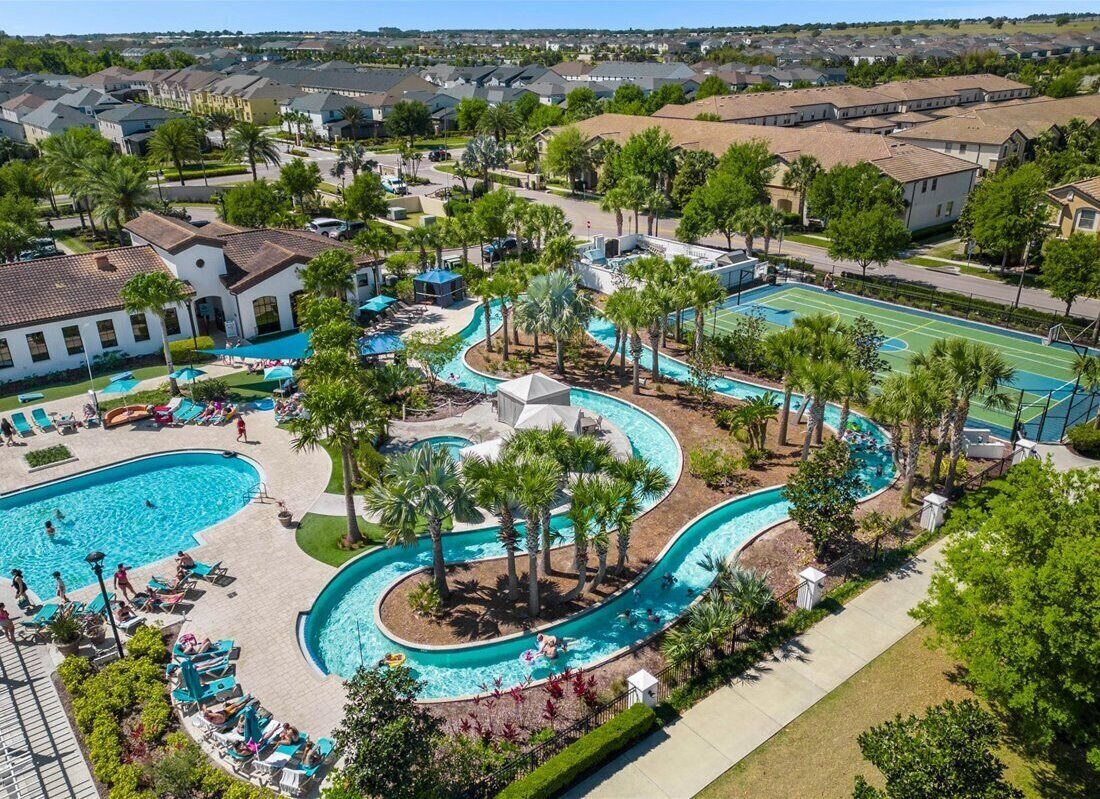 A residential area with a swimming pool, palm trees, and a tennis court.