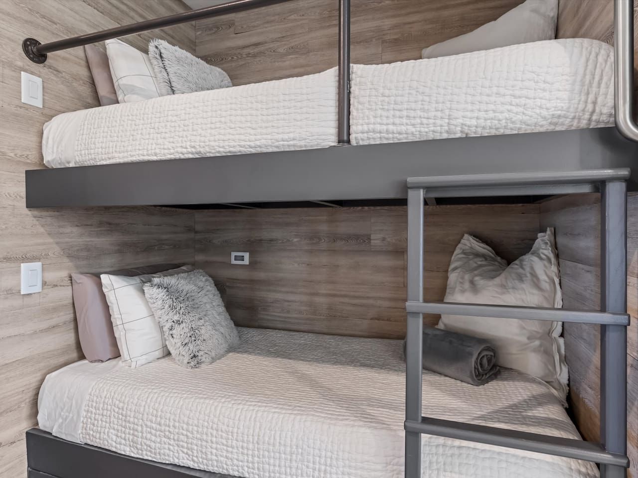 A bunk bed with a ladder, a wooden headboard, and a neutral color scheme.
