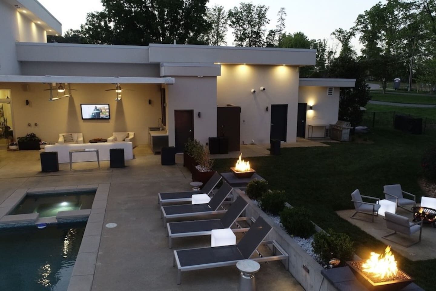 Una casa moderna con piscina, mobiliario exterior y una chimenea.
