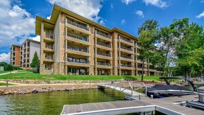Un hôtel à plusieurs étages doté de balcons, d’un quai et donnant sur une étendue d’eau.