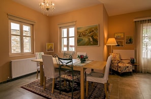 A dining room with a wooden table, chairs, a floral armchair, and a painting on the wall. - Gems of Zagora (Zagora-Mouresi)