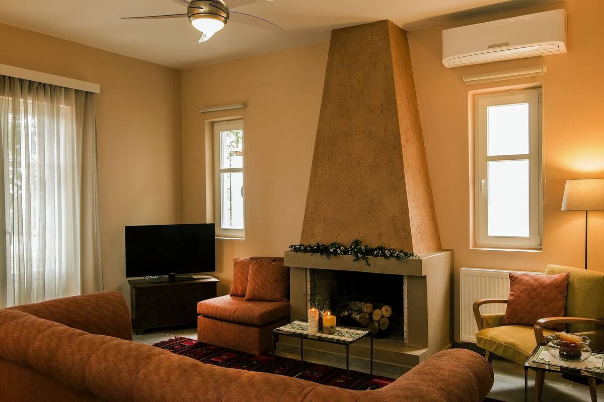 A living room with a fireplace, a television, and seating areas.