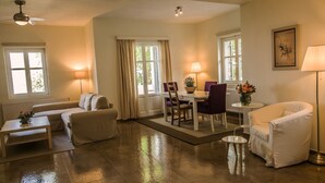 A spacious living room with a sofa, a dining table with chairs, a coffee table, and a floor lamp. - Gems of Zagora (Zagora-Mouresi)