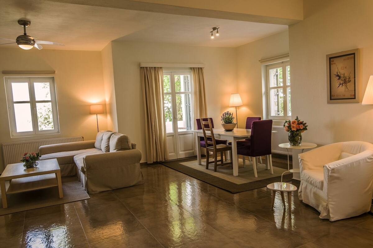 A spacious living room with a sofa, a dining table with chairs, a coffee table, and a floor lamp.