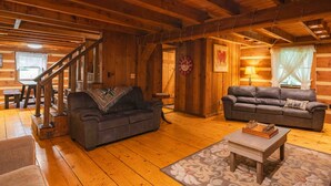 A cozy log cabin interior with two sofas, a coffee table, and a staircase. - My Old Kentucky Home!  Restful Log cabin retreat.. (Madisonville)