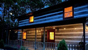 A log cabin with a porch, wooden railings, and a small garden with flowers and a tree. - My Old Kentucky Home!  Restful Log cabin retreat.. (Madisonville)