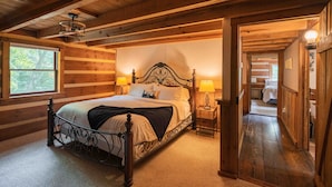 A wooden cabin bedroom with a four-poster bed, two bedside lamps, and a window with a view of trees. - My Old Kentucky Home!  Restful Log cabin retreat.. (Madisonville)
