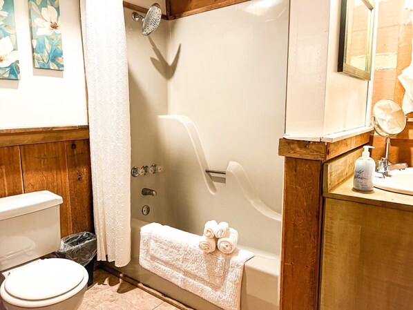 Un baño con bañera, inodoro y lavabo con espejo.