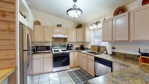 A kitchen with light wooden cabinets, stainless steel appliances, a marble countertop, and a patterned rug. - On Golf Course | Pet Friendly | Nama-Stay (Angel Fire)