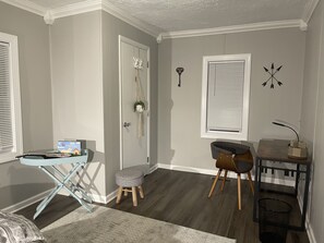 Enjoy a compact retreat with a desk, chair, and stool, plus a window with blinds and a decorative touch.