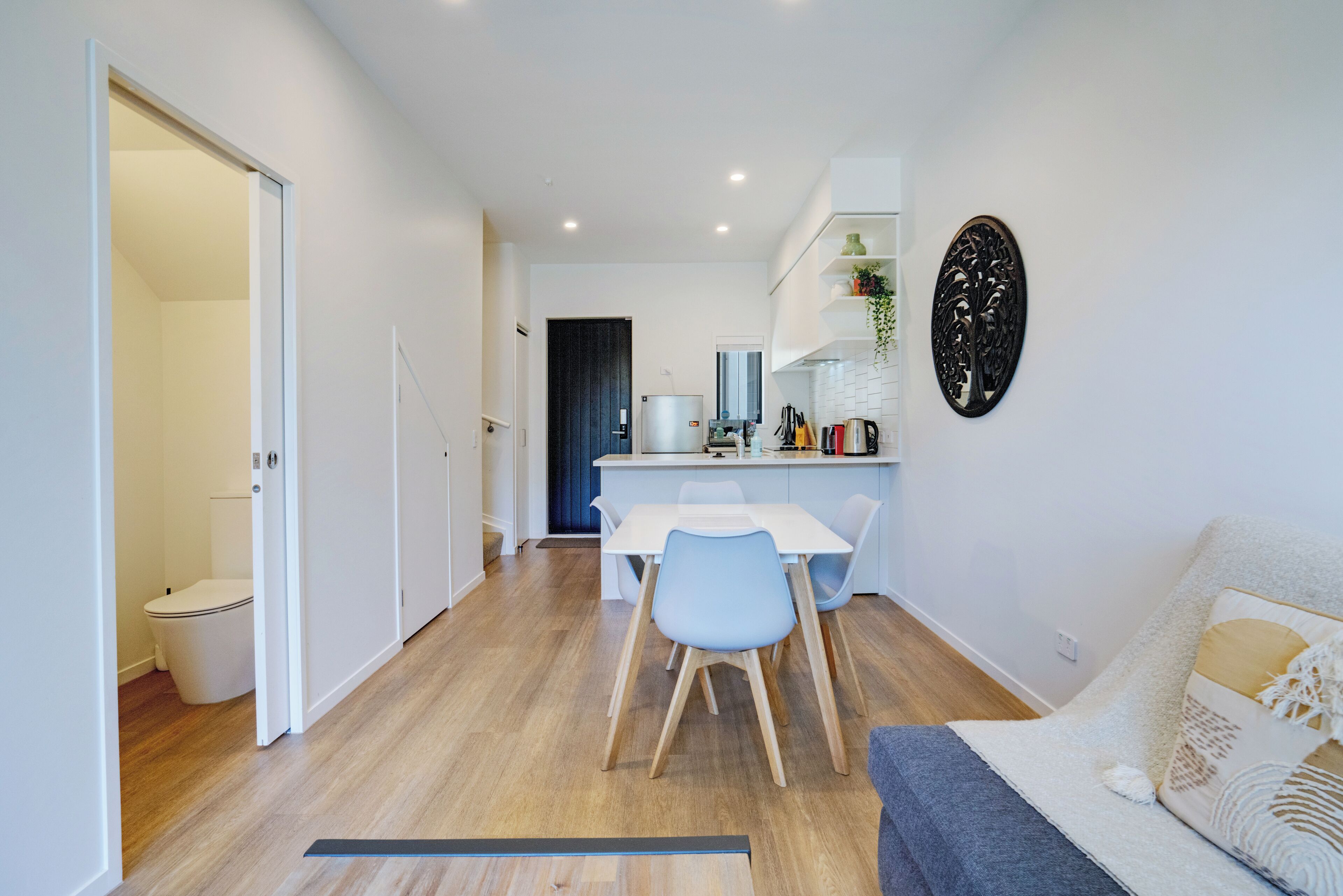 A modern kitchen with white cabinets, a dining table with chairs, and a built-in oven.