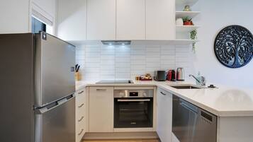 Una cocina moderna con armarios blancos, un refrigerador de acero inoxidable, un horno Bosch y un lavavajillas.