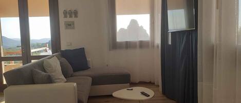 Una sala de estar con un sofá, una mesita redonda y un televisor.