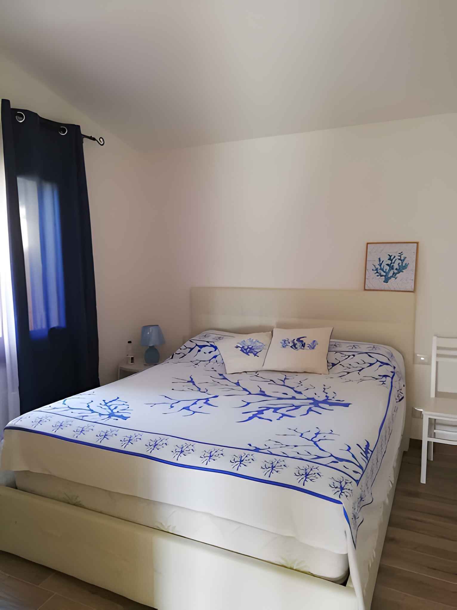 A bedroom with a bed, a nightstand, a lamp, and a framed picture on the wall.