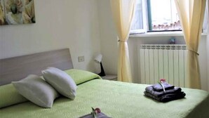 A neatly made bed with green bedding, a pillow, and a folded towel on the side. - Holiday apartment for exclusive use with auxiliary heating (Lurago D'erba)