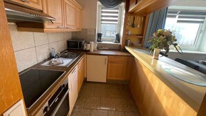 Een kleine keuken met houten kastjes, een magnetron, een broodrooster en een spoelbak.