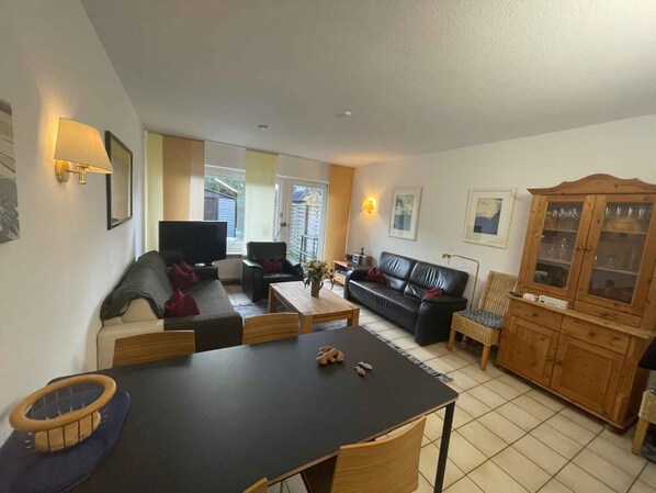 Una sala de estar con sofá, televisor, mesa de comedor y aparador.