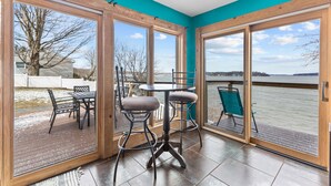 Una habitación con un amplio ventanal corredera que da a una terraza con mobiliario exterior.