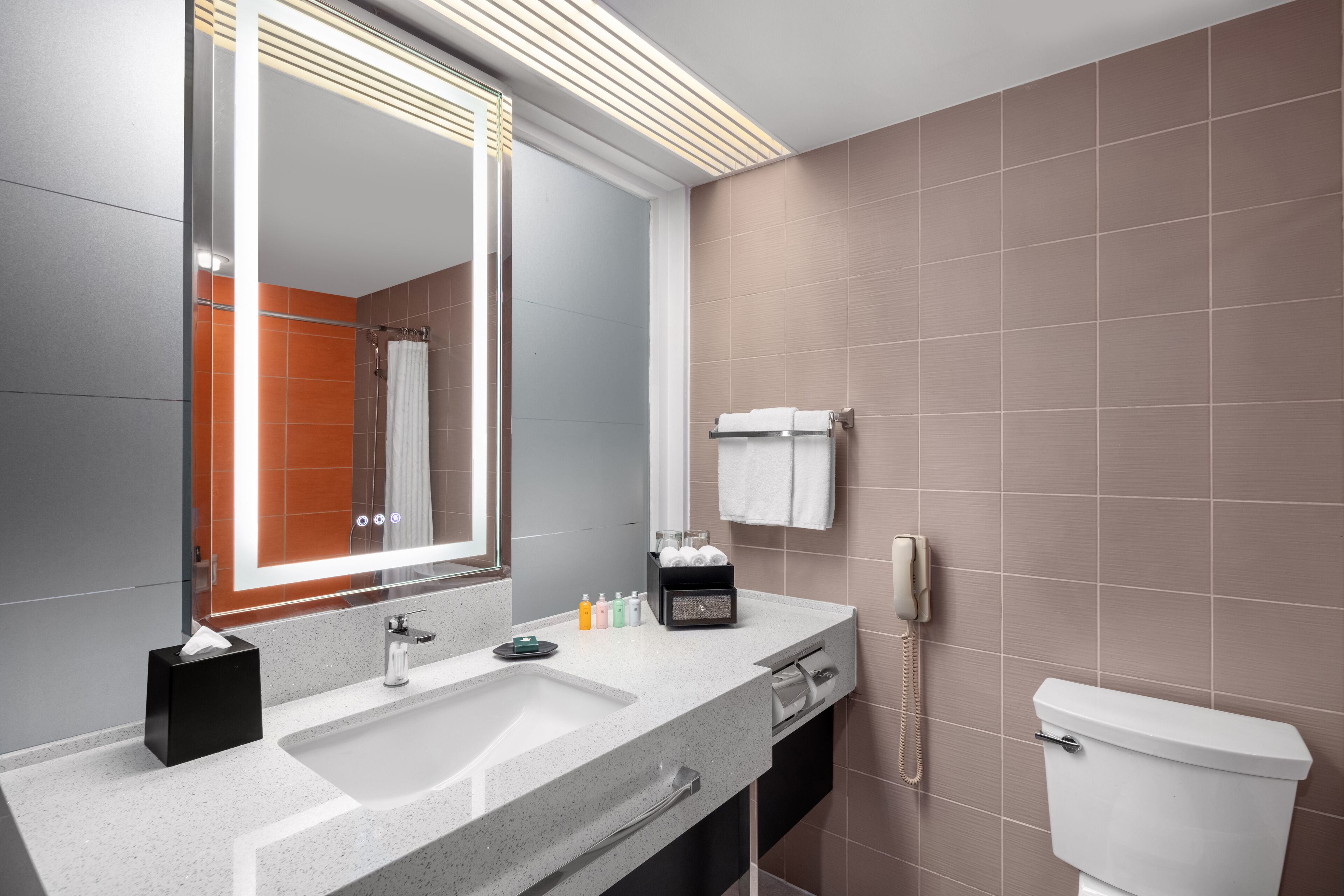 Un baño moderno con un espejo grande, un lavabo, un inodoro y un perchero para toallas.