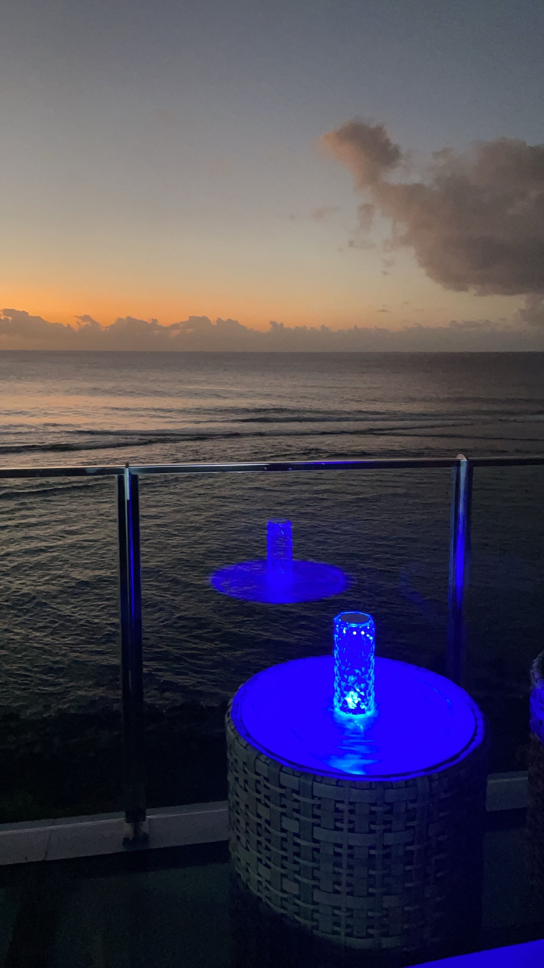 A balcony with a view of the ocean at sunset.