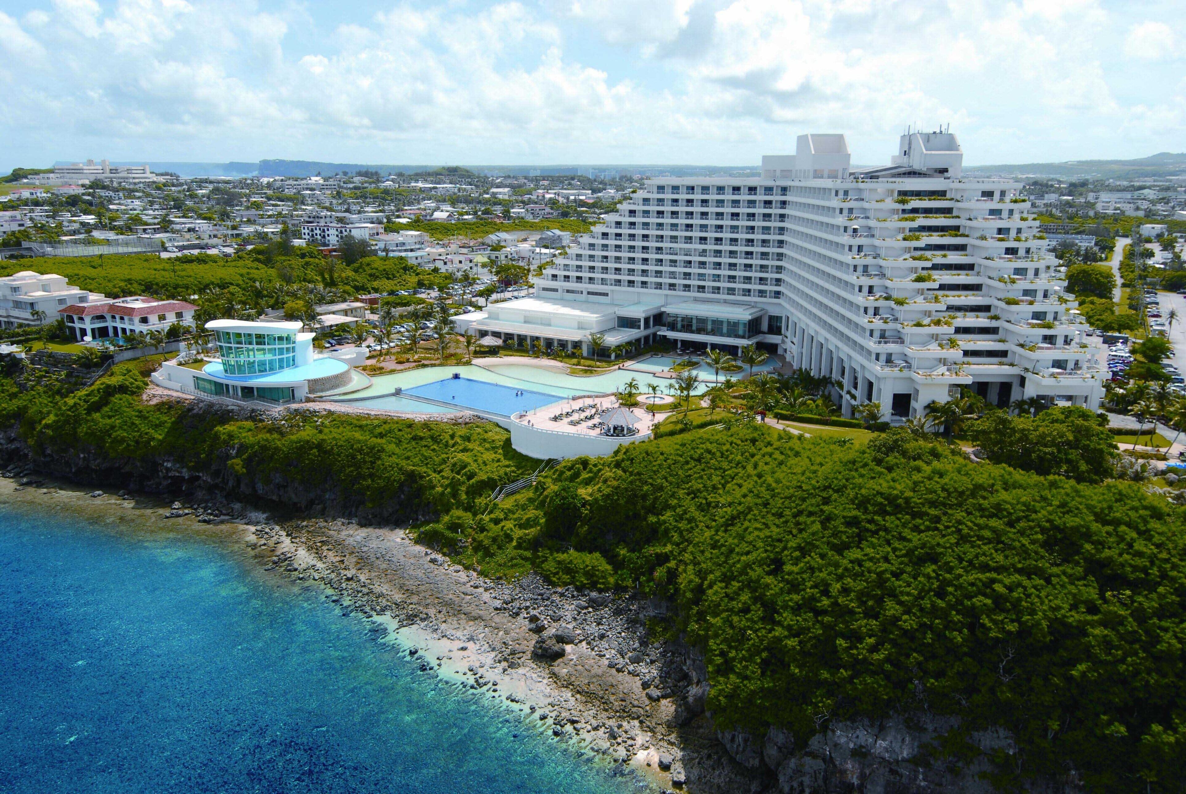 A large resort with multiple buildings, a swimming pool, and a beach area.