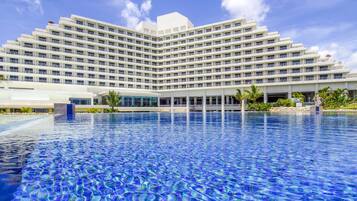 Un hotel grande con un diseño moderno, que cuenta con un amplio área de piscina al frente.