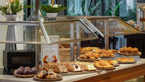 A buffet counter with various pastries and breads, a microwave, and potted plants.
