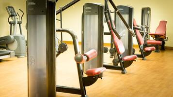 Un gimnasio con diversas máquinas de ejercicio, incluyendo elípticas y máquinas de pesas.