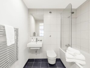 Een moderne badkamer met toilet, wastafel en douche.