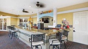 A spacious bar area with a central island, multiple seating options, and a visible kitchen area with a large screen. - ★SPACIOUS 4BD/2BA★CONVENTION CENTER/ UNIVERSAL EPIC UNIVERSE WALKING DISTANCE (Orlando)