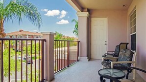 A balcony with a view of a residential street, a door, and two chairs. - ★SPACIOUS 4BD/2BA★CONVENTION CENTER/ UNIVERSAL EPIC UNIVERSE WALKING DISTANCE (Orlando)