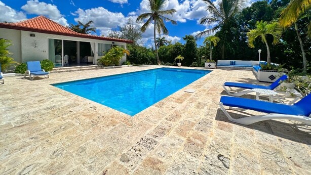 Ein Pool mit blauem Wasser, umgeben von Liegestühlen und Palmen.