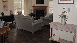Un salon avec une cheminée, un téléviseur fixé au-dessus et un tableau encadré au mur.