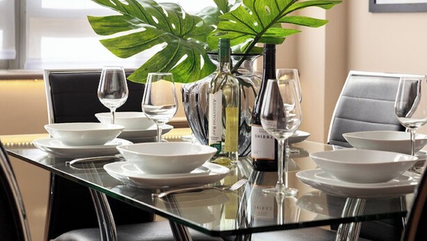 A dining table set with white plates, glasses, and a bottle of wine. - Lawrence House by Interhome (London City)